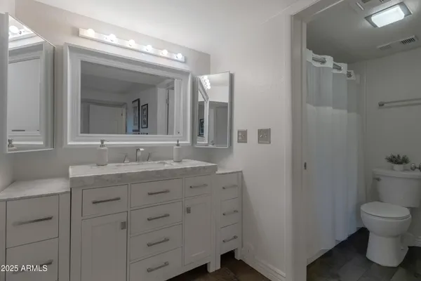 a bathroom with a granite countertop sink mirror and toilet