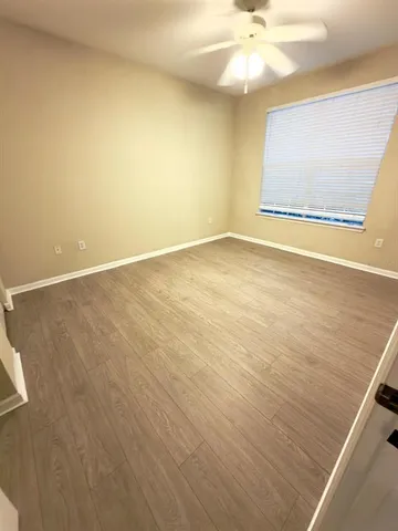 an empty room with a ceiling fan and window