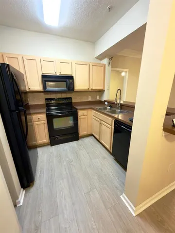 a kitchen with granite countertop a refrigerator stove and sink