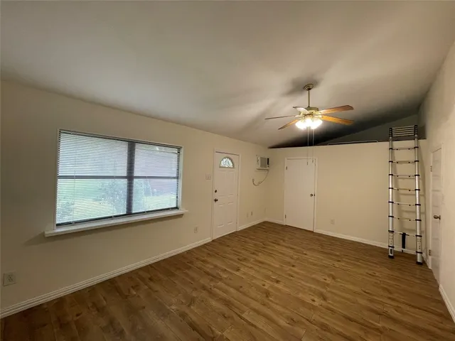 an empty room with chandelier fan and windows