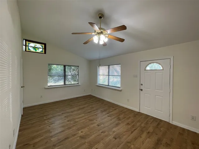 a view of an empty room with window and chandelier fan