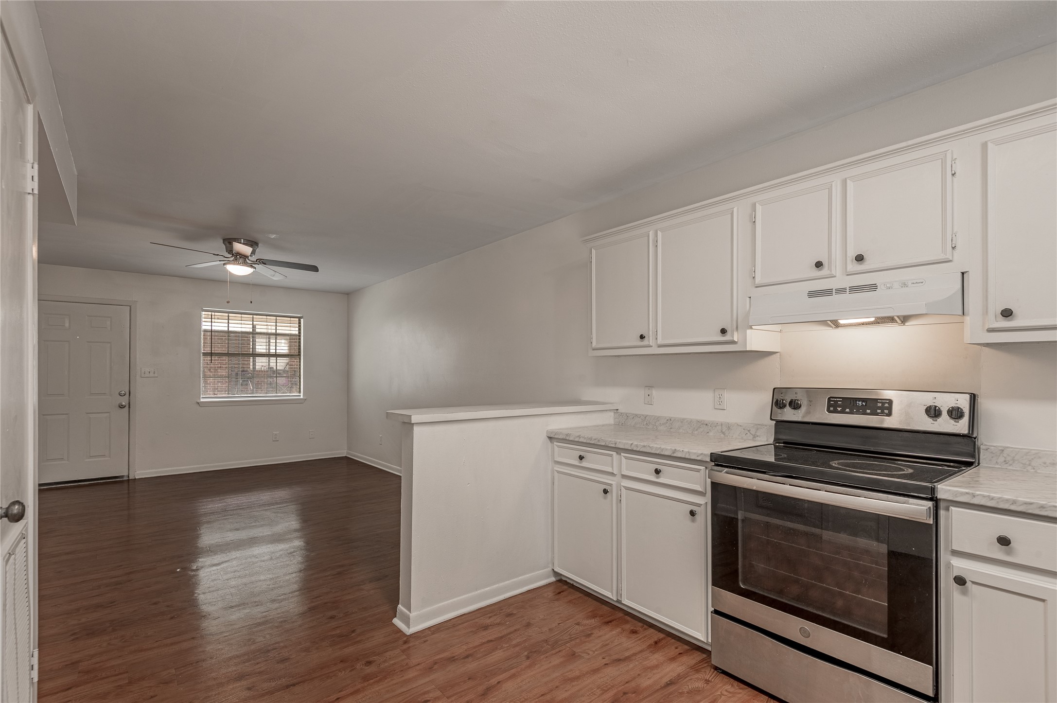 600 Palm Street, Unit 12 Huntsville, TX 77340 - Photo 11 of 23 a kitchen with granite countertop a stove a sink and white cabinets with wooden floor