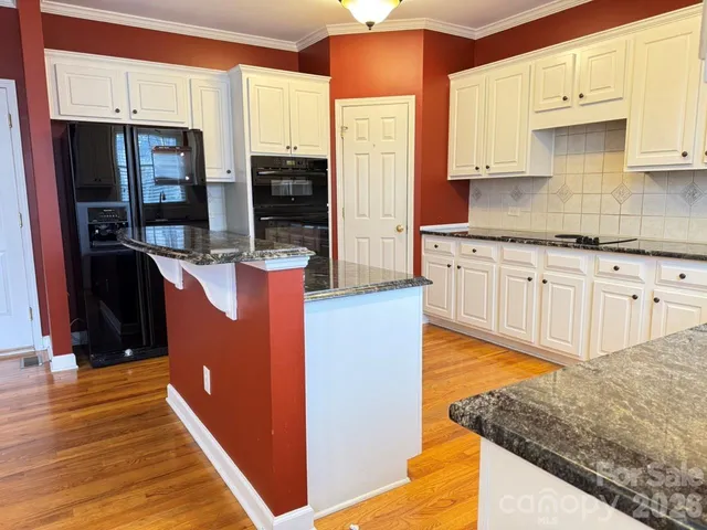 a kitchen with stainless steel appliances granite countertop a refrigerator a stove and a sink