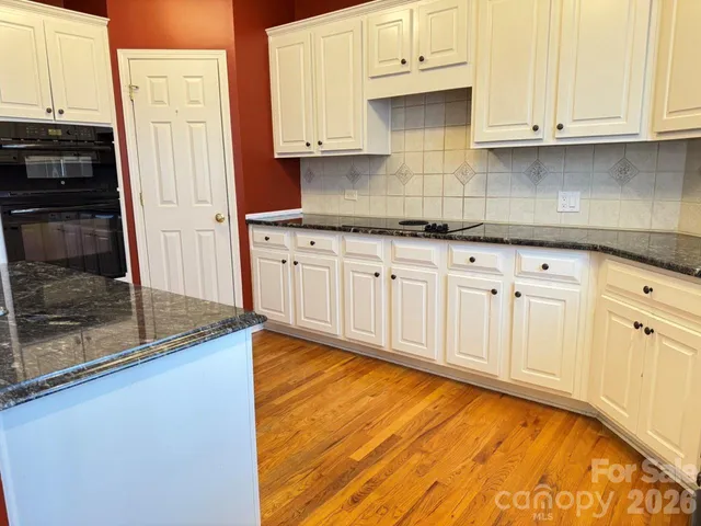 a kitchen with granite countertop white cabinets and stainless steel appliances