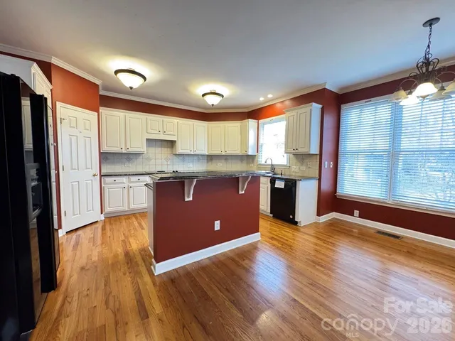 a large kitchen with stainless steel appliances granite countertop a stove a sink dishwasher and a refrigerator with wooden floor