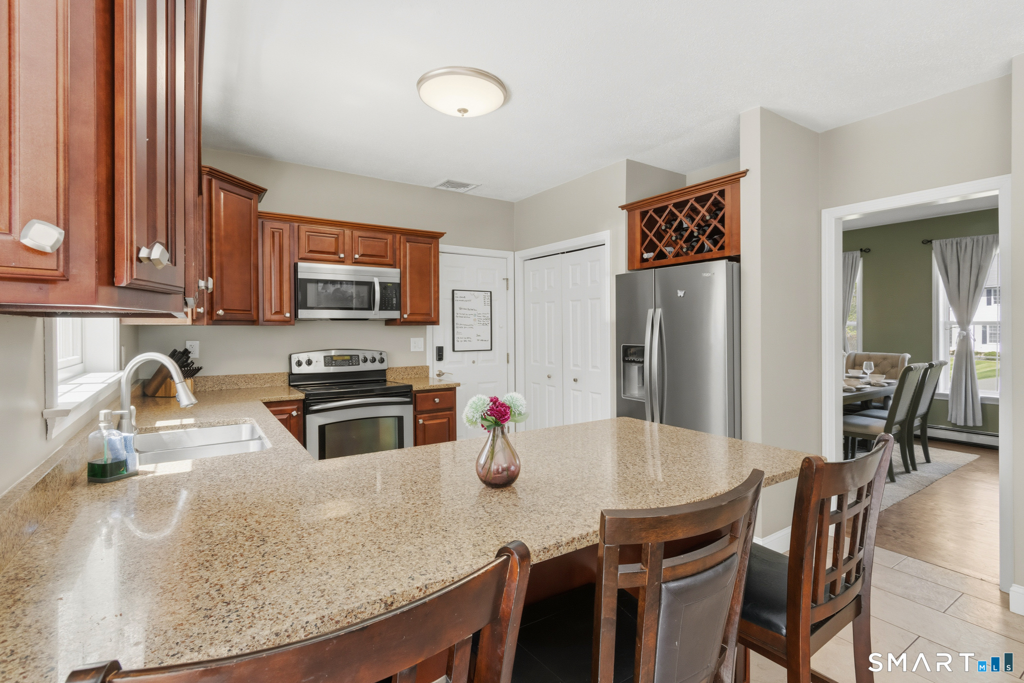 5 Ice Pond Road Granby, CT 06035 - Photo 8 of 40 a kitchen with stainless steel appliances granite countertop a stove a refrigerator a sink a dining table and chairs with wooden floor