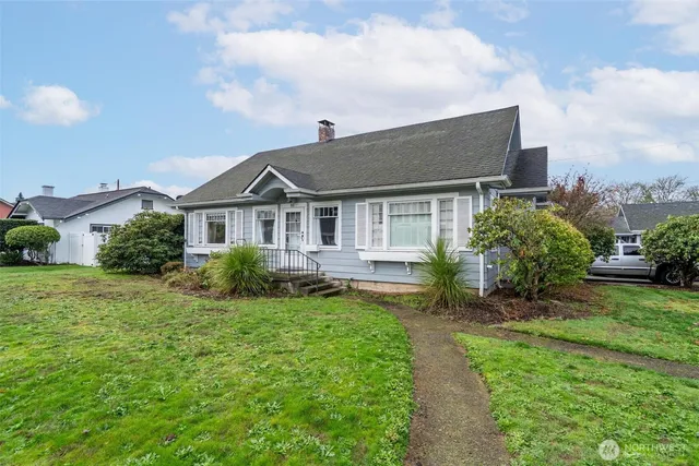 a view of a house with a yard plants and large tree