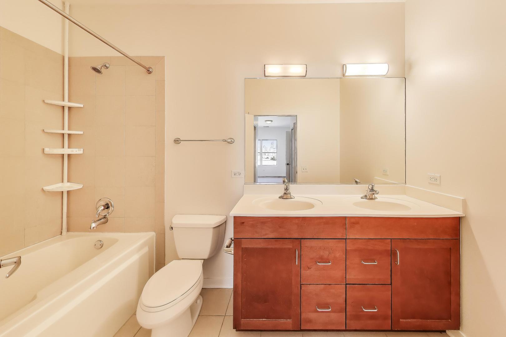 1155 West Roosevelt Road, Unit 412 Chicago, IL 60608 - Photo 21 of 31 a bathroom with a toilet sink and mirror