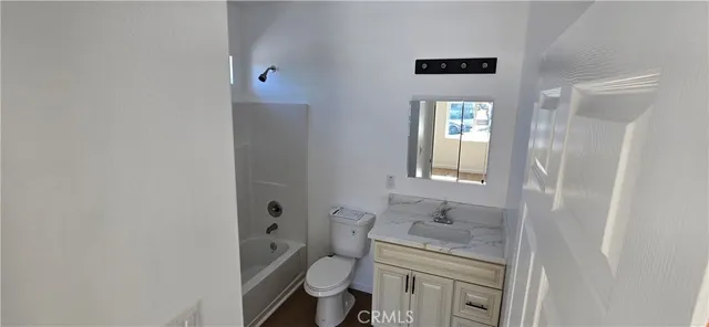 a bathroom with a granite countertop toilet a sink and a mirror