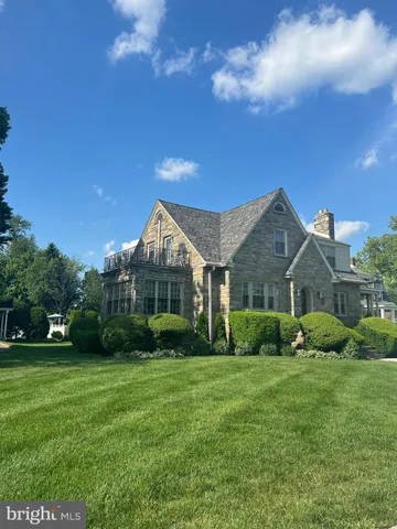 a view of a big yard in front of a brick house with large windows