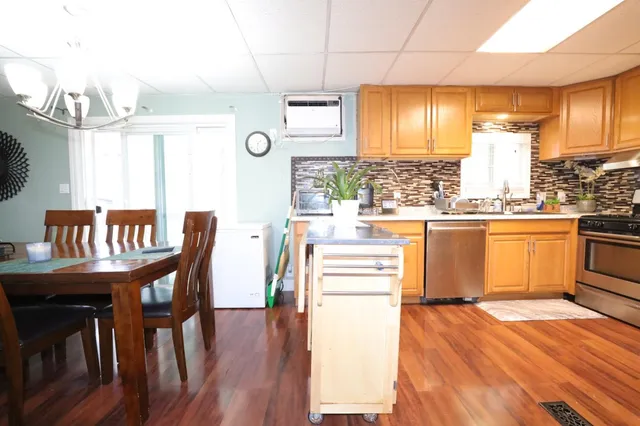 a kitchen with stainless steel appliances granite countertop a stove top oven a dining table and chairs with wooden floor