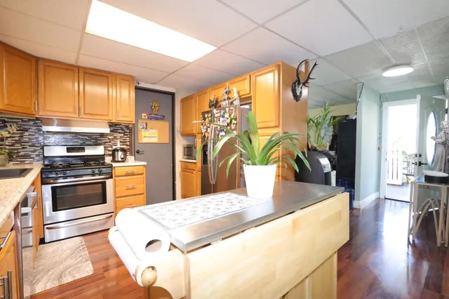 a kitchen with stainless steel appliances granite countertop a stove a refrigerator a oven a sink with island and chairs