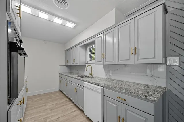 a kitchen with granite countertop a sink stainless steel appliances and cabinets