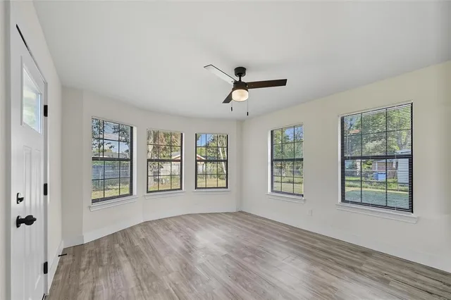a view of an empty room with a window and wooden floor