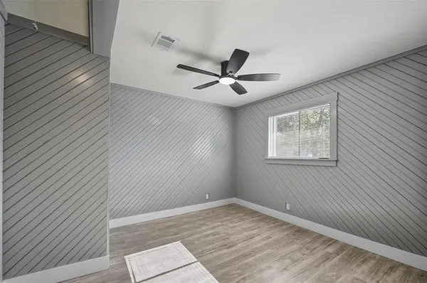 an empty room with wooden floor and ceiling fan