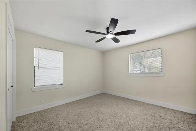 an empty room with a window and a ceiling fan