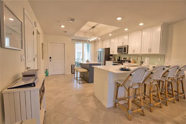 a kitchen with stainless steel appliances kitchen island granite countertop a stove a sink a refrigerator and white cabinets