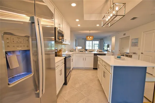 a kitchen with stainless steel appliances kitchen island granite countertop a refrigerator and a sink
