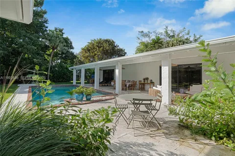a view of a patio with table and chairs potted plants and floor to ceiling window