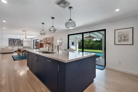 a kitchen with stainless steel appliances granite countertop a sink a stove top oven a wooden floor