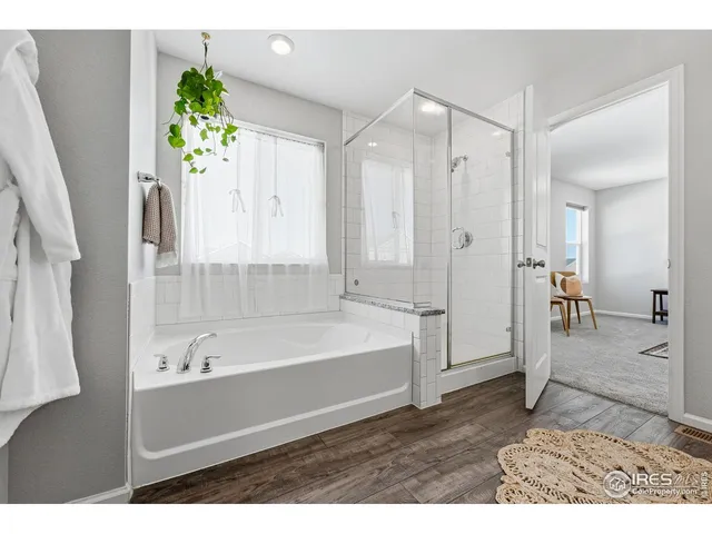 a bedroom with a large bed a potted plant on dresser and a wooden floor