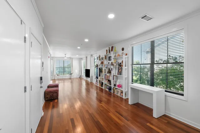 a view of a kitchen with kitchen island a sink wooden floor and a large window