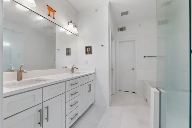 a spacious bathroom with a double vanity sink a mirror and a shower