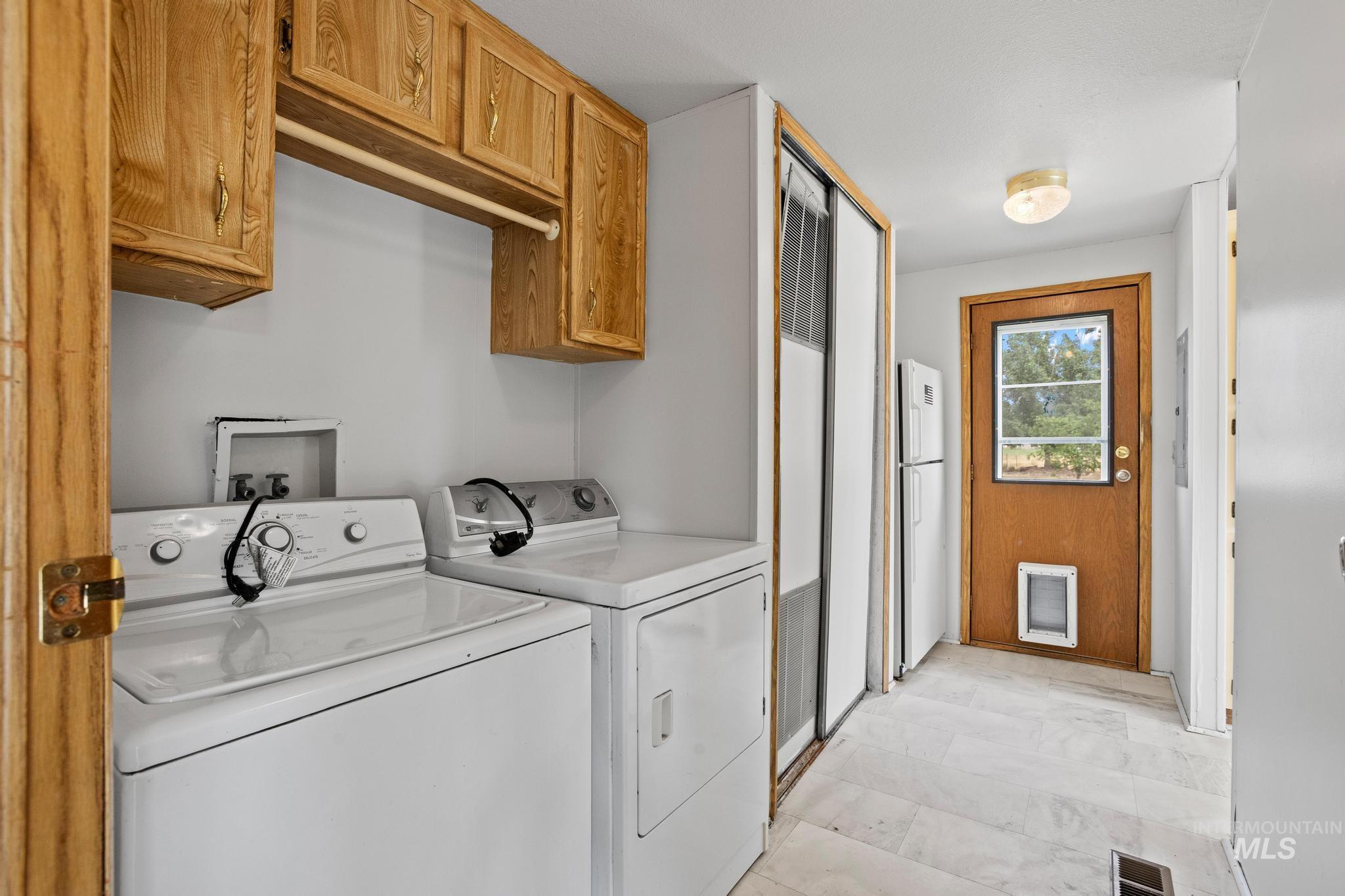3680 South Mill Road Emmett, ID 83617 - Photo 21 of 38 Dedicated laundry area featuring overhead wood-finish cabinetry, a built-in hanging rod, and light-toned flooring