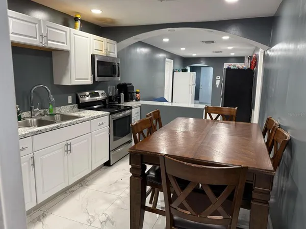 a kitchen with stainless steel appliances a table chairs sink and microwave