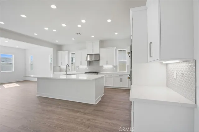 a large white kitchen with kitchen island a sink a stove a refrigerator and white cabinets