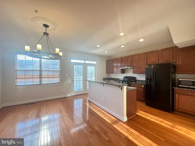 a kitchen with stainless steel appliances granite countertop a refrigerator a sink dishwasher a stove and white countertops with wooden floor