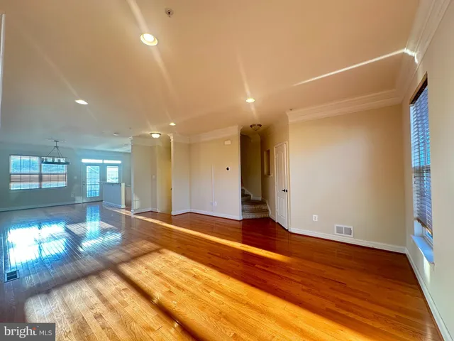 a view of an empty room with window and wooden floor