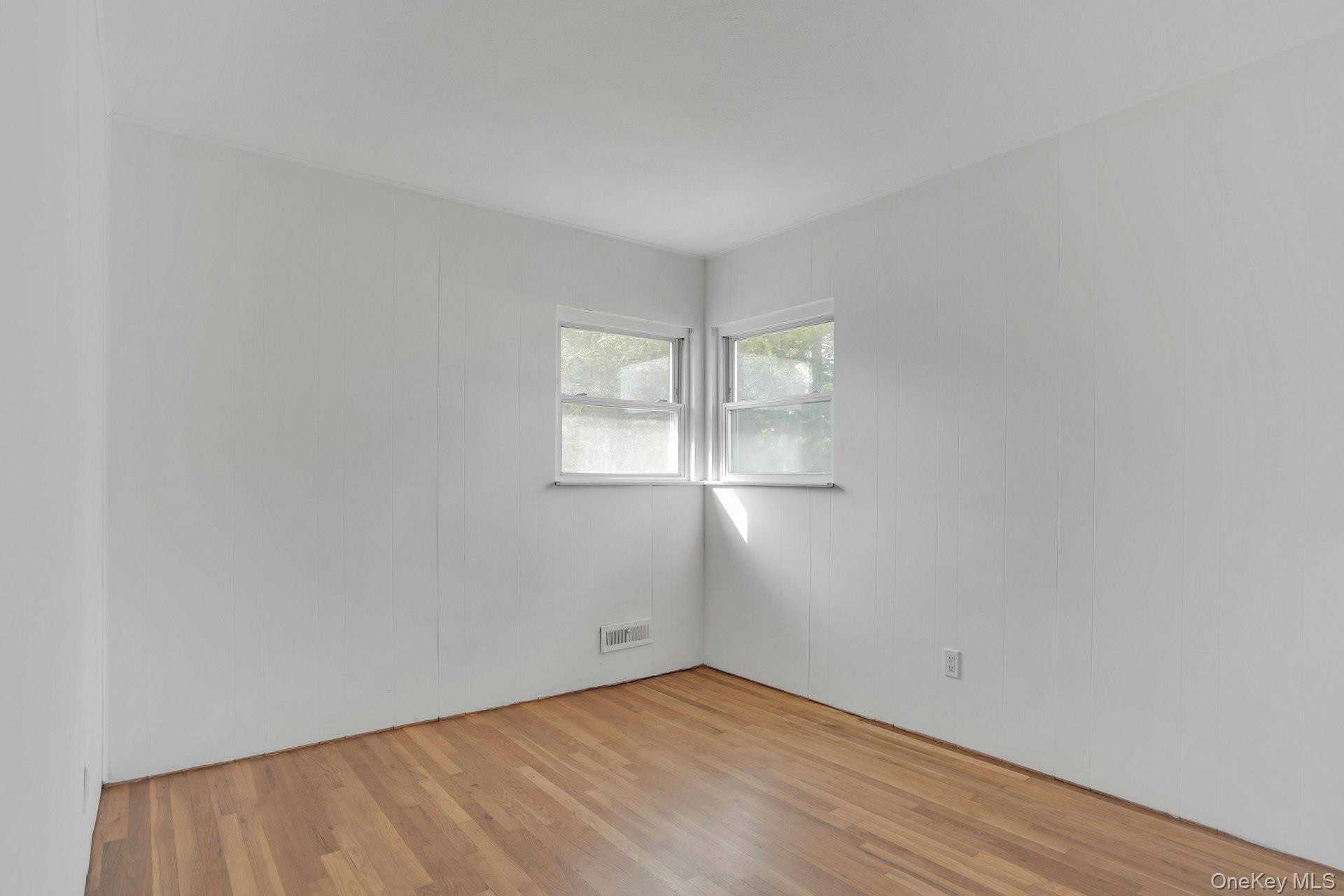 44 Delaware Avenue Commack, NY 11725 - Photo 17 of 34 an empty room with wooden floor and windows
