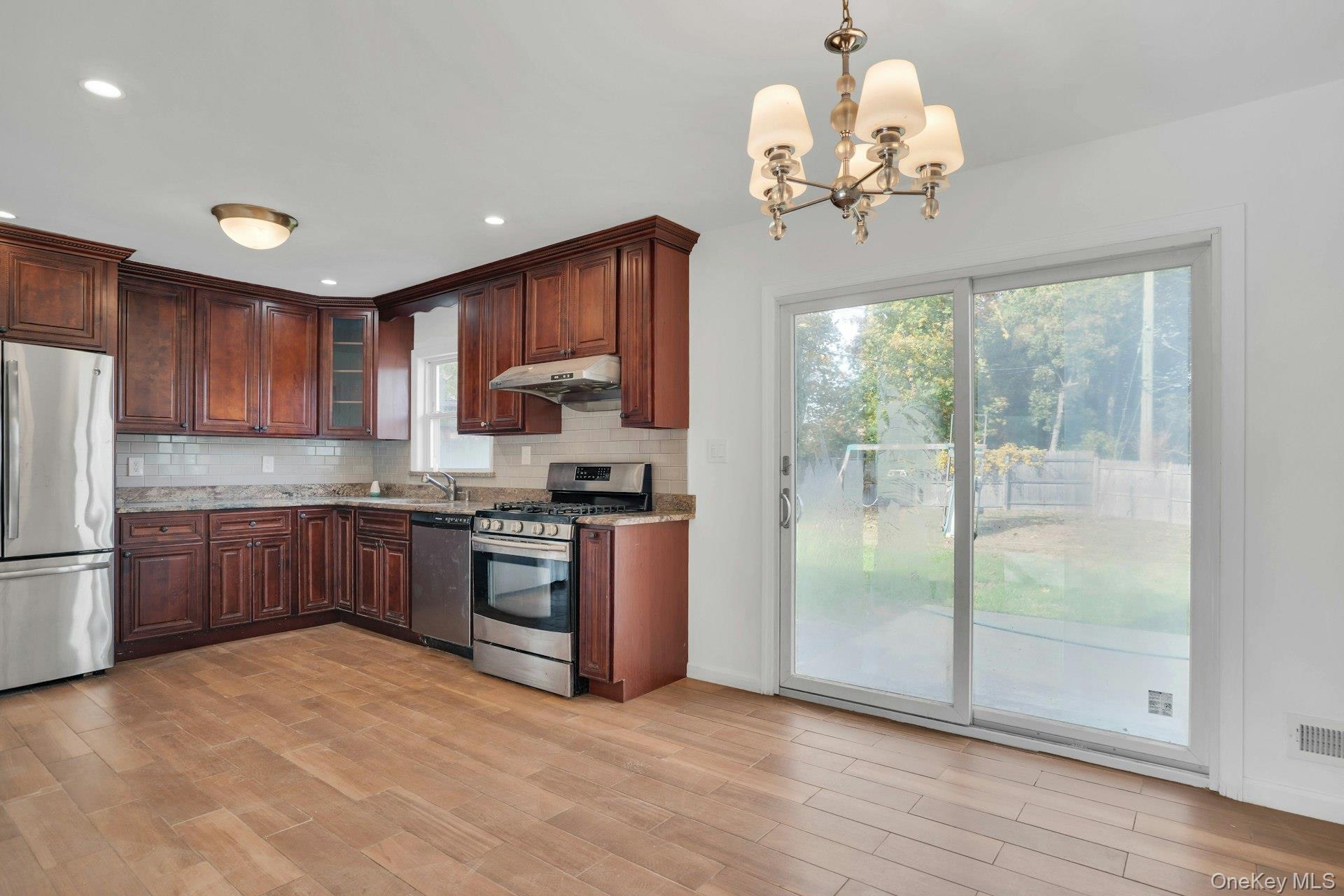 44 Delaware Avenue Commack, NY 11725 - Photo 10 of 34 a kitchen with stainless steel appliances granite countertop a refrigerator a sink dishwasher a stove with wooden cabinets and floor