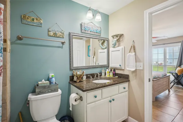 a bathroom with a granite countertop toilet sink and mirror
