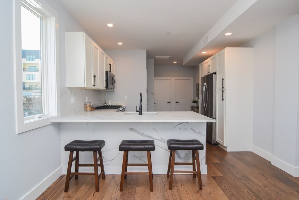 3850 Washington Street, Unit 1 Boston, MA 02131 - Photo 12 of 23 a kitchen with stainless steel appliances a table and chairs in it