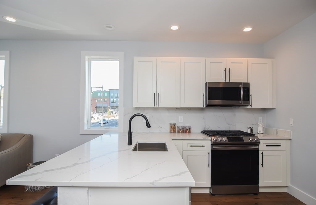 3850 Washington Street, Unit 1 Boston, MA 02131 - Photo 8 of 23 a kitchen with stainless steel appliances a sink a stove a microwave cabinets and a window