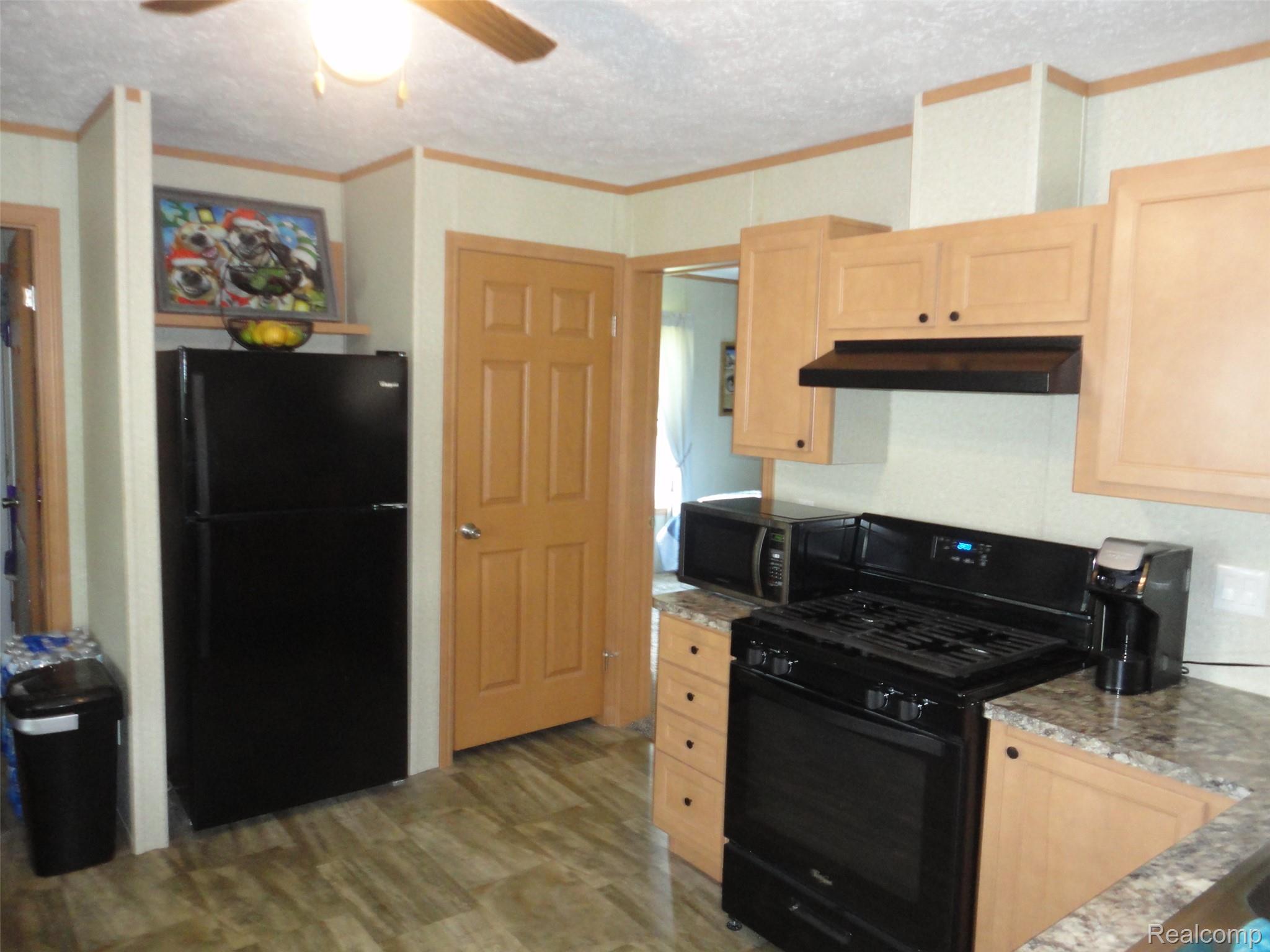 463 Edinborough Temperance, MI 48182 - Photo 5 of 23 Kitchen featuring wood-finish flooring, light wood cabinetry, stone-look countertops, and black appliances including a range with an overhead vent