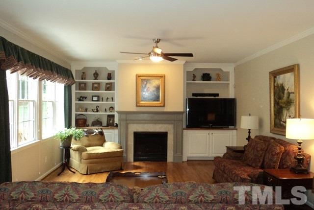 6900 Wilderness Road Raleigh, NC 27613 - Photo 4 of 25 a living room with furniture a flat screen tv and a fireplace