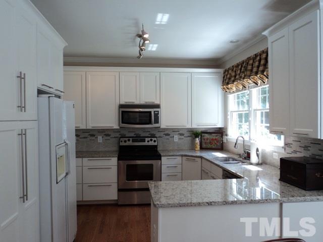 6900 Wilderness Road Raleigh, NC 27613 - Photo 8 of 25 a kitchen with stainless steel appliances granite countertop a sink stove and refrigerator