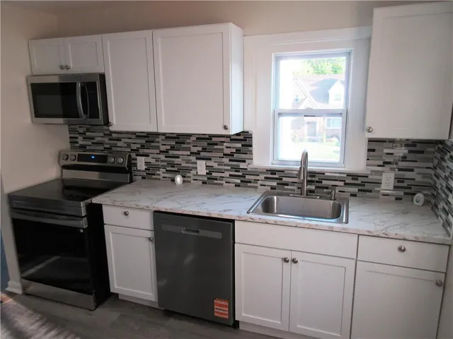 a kitchen with granite countertop white cabinets and stainless steel appliances