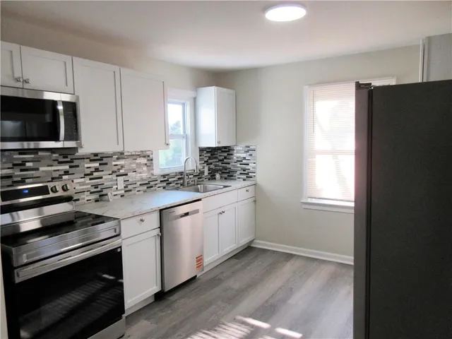 an empty room with wooden floor fireplace and windows