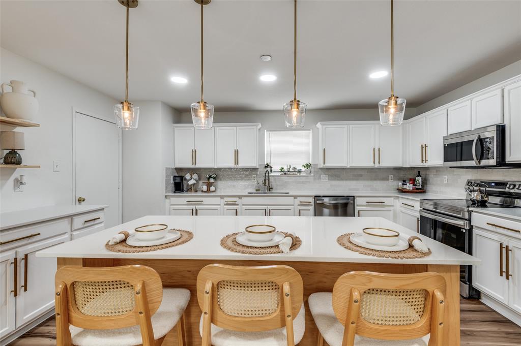 2416 Big Spring Drive Fort Worth, TX 76120 - Photo 15 of 36 a kitchen with stainless steel appliances granite countertop a sink a stove a kitchen island with chairs and white cabinets