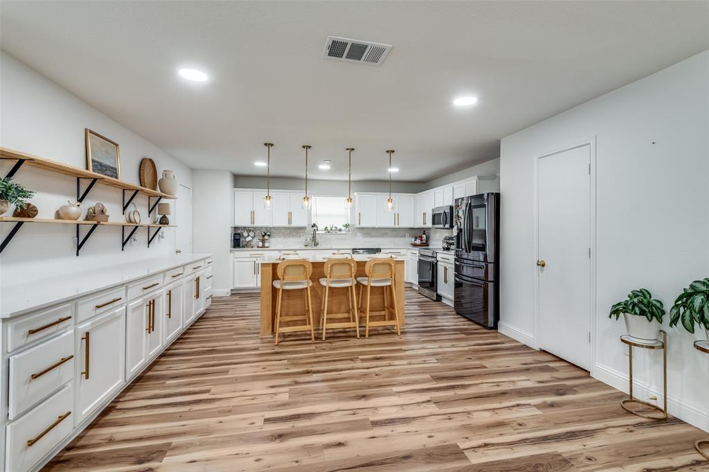 2416 Big Spring Drive Fort Worth, TX 76120 - Photo 16 of 36 a kitchen with stainless steel appliances kitchen island granite countertop a table chairs in it and a wooden floors