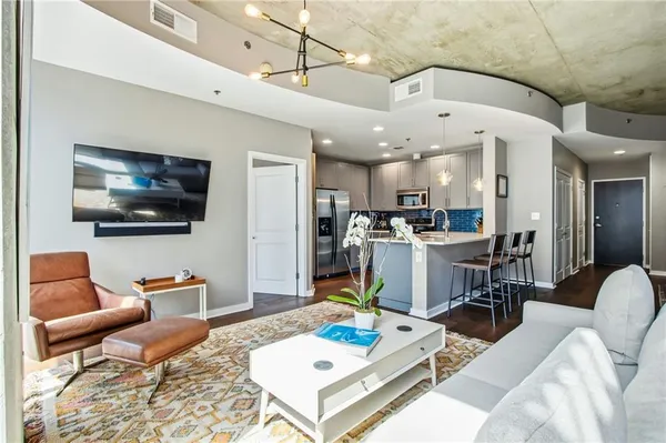 a living room with furniture kitchen view and a flat screen tv
