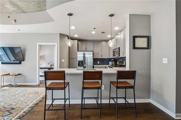 a kitchen with stainless steel appliances kitchen island granite countertop a dining table chairs and a refrigerator a sink