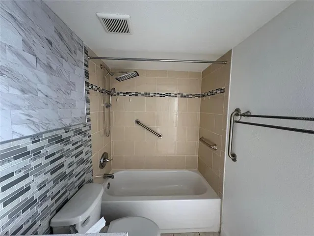 a bathroom with a granite countertop bathtub shower and toilet