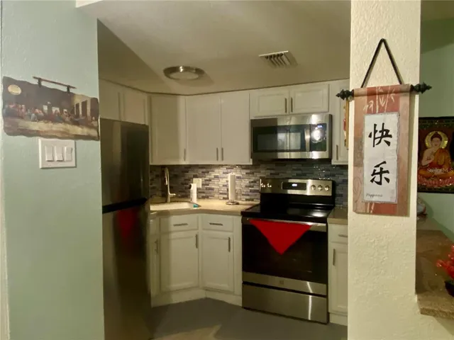 a kitchen with stainless steel appliances granite countertop a refrigerator a stove top oven and a sink