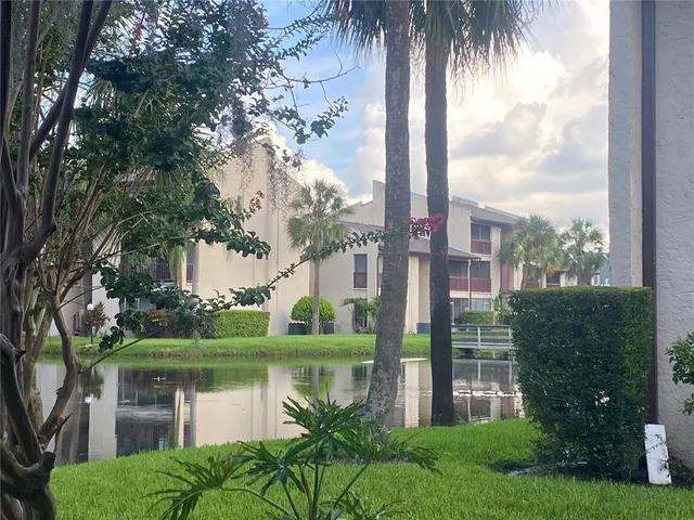 a front view of a house with garden and lake