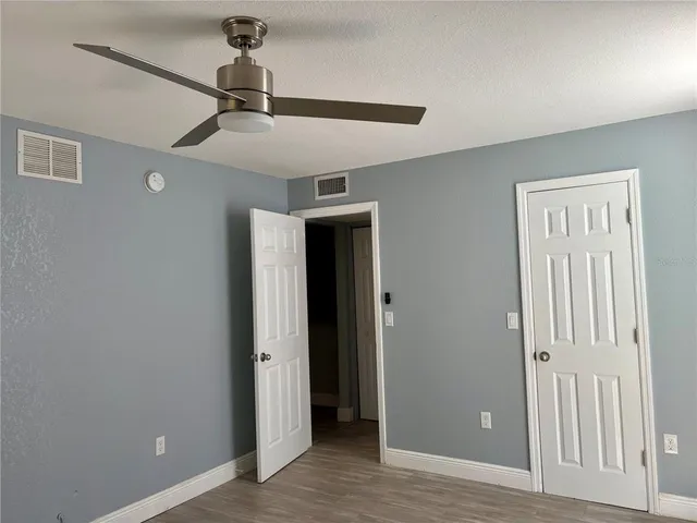 an empty room with closet and a ceiling fan